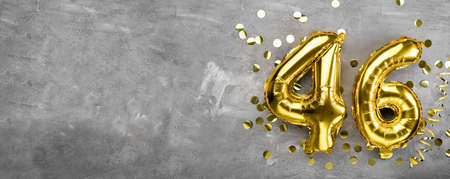 Yellow foil balloon number, number forty six concrete background. Greeting card with the inscription 46. Anniversary concept. for anniversary, birthday, new year celebration. banner, copy space.の写真素材