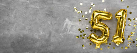Yellow foil balloon number, number fifty one concrete background. Greeting card with the inscription 51. Anniversary concept. for anniversary, birthday, new year celebration. banner, copy space.の写真素材