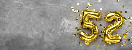 Yellow foil balloon number, number fifty two concrete background. Greeting card with the inscription 52. Anniversary concept. for anniversary, birthday, new year celebration. banner, copy space.の写真素材