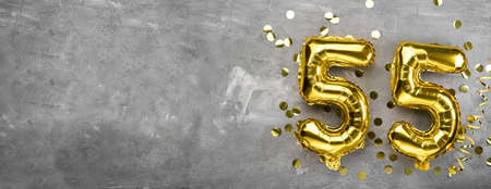 Yellow foil balloon number, number fifty five concrete background. Greeting card with the inscription 55. Anniversary concept. for anniversary, birthday, new year celebration. banner, copy space.の写真素材