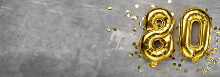 Yellow foil balloon number, number eighty on a concrete background. Greeting card with the inscription 80. Anniversary concept. for anniversary, birthday, new year celebration. banner, copy space.の写真素材