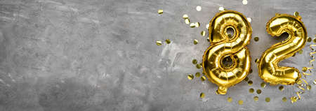 Yellow foil balloon number, number eighty two on a concrete background. Greeting card with the inscription 82. Anniversary concept. for anniversary, birthday, new year celebration. banner, copy space.の写真素材