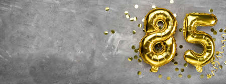 Yellow foil balloon number, number eighty-five on a concrete background. Greeting card with the inscription 85. Anniversary concept. for anniversary, birthday, new year celebration. banner,の写真素材