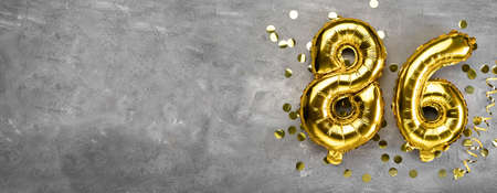 Yellow foil balloon number, number eighty six on a concrete background. Greeting card with the inscription 86. Anniversary concept. for anniversary, birthday, new year celebration. banner,の写真素材