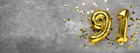 Yellow foil balloon number, number ninety one on a concrete background. Greeting card with the inscription 91. Anniversary concept. for anniversary, birthday, new year celebration. banner,の写真素材