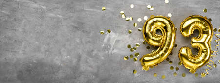 Yellow foil balloon number, number ninety-three on a concrete background. Greeting card with the inscription 93. Anniversary concept. for anniversary, birthday, new year celebration. banner,の写真素材