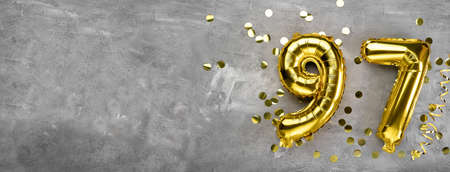 Yellow foil balloon number, number ninety-seven on a concrete background. Greeting card with the inscription 97. Anniversary concept. for anniversary, birthday, new year celebration. banner,の写真素材