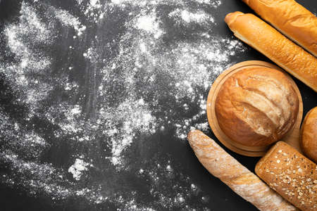 assortment of fresh bread on black background with flour, top view, copy space. Homemade freshly baked various wheat and rye bread loaves. bakeryの写真素材