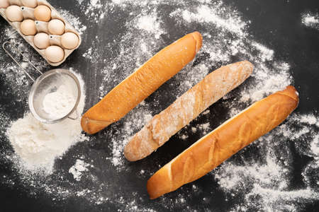 view photo of a variety of french baguette on a black board background eggs sieve and flour. Still life captured from above banner. copyspace.の写真素材