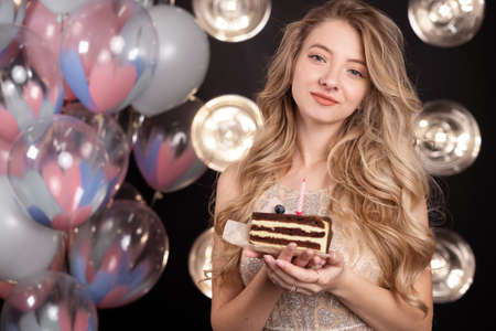 Romantic woman in a dress holds a delicious cake on a plate against the background of balloons. The concept of celebrating folk holidays birthday. close-up portrait.の写真素材