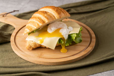 for breakfast sandwich with croissant with poached egg, on a plate. copy spaceの写真素材