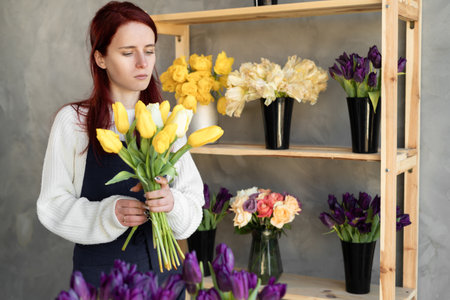 Woman florist works. Young pretty lady makes a bouquet of yellow tulips. Great gift for mothers day or valentines day.の写真素材