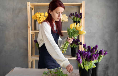 Woman florist works. A young pretty lady makes a bouquet of different tulips. Great gift for mothers day or valentines day.の写真素材