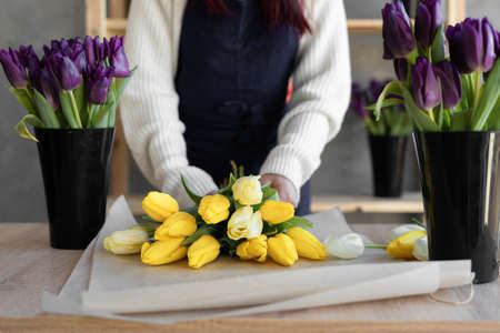 Close-up of female hands make a bouquet of tulips. Florist workplace. Preparing a gift for a loved one.の写真素材