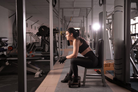 Athletic woman sits and rests after training or exercising in the fitness room. Relaxation concept....