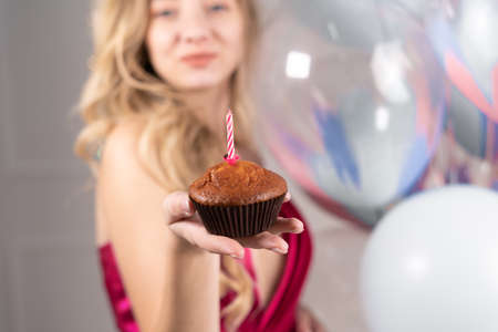 Closeup female hand holding cupcake with candles birthday celebration concept.の写真素材