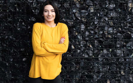 Caucasian woman in orange sweater on black stone background, close-up coal stones behind bars and girl, people concept isolatedの写真素材
