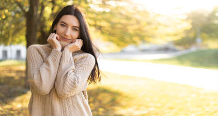Brunette portrait in autumn park, caucasian woman in warm sweater walks in september outdoors, autumn concept, bannerの写真素材