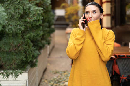 young woman having a street conversation on the phone fear and emotions on her face, bad news close-up caucasian brunette, technology and people conceptの写真素材