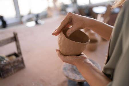 DIY work close-up of a creative woman sculpting a bowl from raw clay in a pottery workshop during a master class or workshop. The concept of craft and craftswoman.の写真素材
