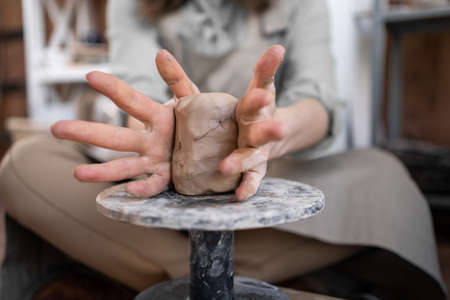 A woman works on a potters wheel. An artisan molds a cup from a clay pot. Workshop of hand molding.の写真素材