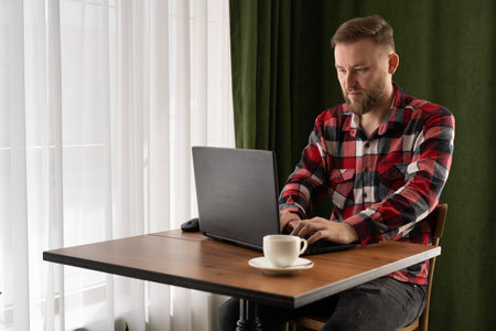 freelancing concept, caucasian freelancer working in cafe with laptop, remote work, student typing on keyboard pc sitting in coffee shopの写真素材