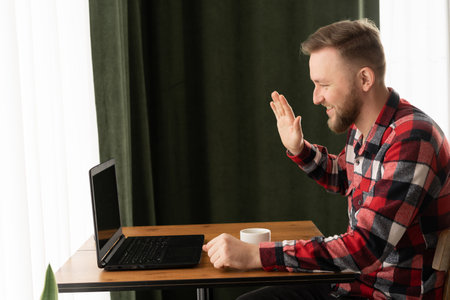 Smiling handsome man having video call in cafe, bearded businessman talking on video call with...