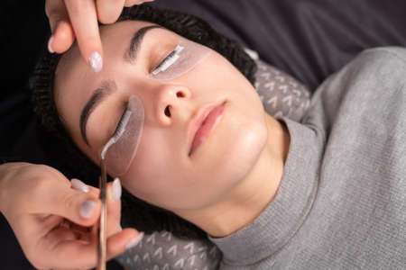 eyelash extension procedure. Young woman in a spa salon. beauty sphere concept.の写真素材
