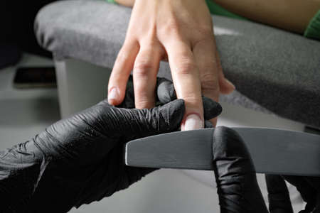Manicure care spa salon. Close-up of a master with a nail file makes the shape of the nails. selective focus.の写真素材