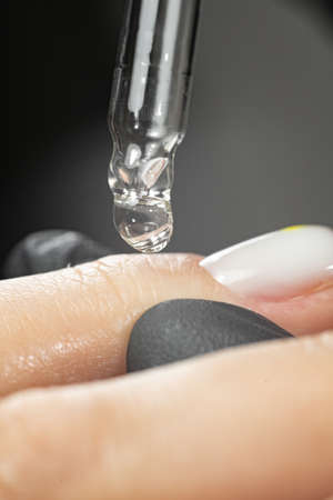 pipette with a drop of nail care products or care products close-up. The concept of a beauty salon and a beautiful manicure.の写真素材