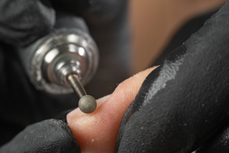 Hardware professional manicure, cleaning the skin around the nail with a cutter. Close up female hands in a beauty salon. Fingernail treatment, manufacturing process. close upの写真素材