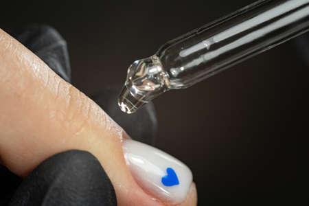 pipette with a drop of nail care products or care products close-up. The concept of a beauty salon and a beautiful manicure.の写真素材