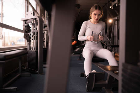caucasian muscular woman performs traction exercise on the waist and pumps back muscles in the gym alone. copyspace.の写真素材
