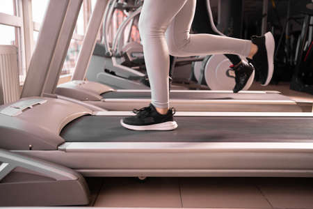 Close-up of sneakers female muscular legs while running on a treadmill in the morning in the fitness room,の写真素材