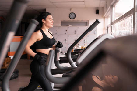 caucasian attractive young athletic woman is training in the gym. Doing cardio on the treadmill. Running on a treadmill.の写真素材