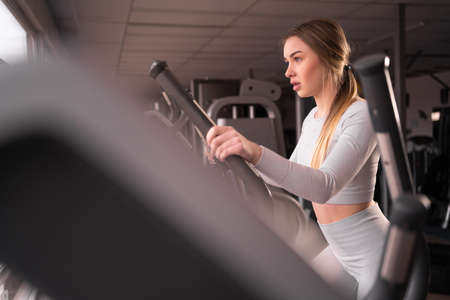 caucasian attractive young athletic woman is training in the gym. Woman exercising on a cardio machineの写真素材