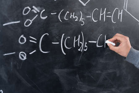 study of chemistry concept, chemist hand draws formulas and elements with chalk on the blackboard, signs and symbols of chemistry, organic science, lesson at schoolの写真素材