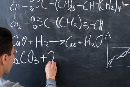 Chemistry lesson, chemist student or teacher writes formulas with chalk on blackboard, chalkboard and man handwritten, chemistry science education conceptの写真素材