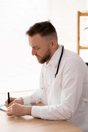Consultation, a doctor working in a hospital writes a prescription, healthcare and medical concept, a doctor in a white coat with a stethoscope.の写真素材