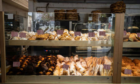 showcase of pastry shop selling dessert cannoli, cakes and pies with price tags through display glass window, lots of pastries in pastry shopの写真素材