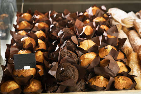 a lot of muffins or cupcakes on the shop window, homemade baking concept, sweets shop and honey chocolate cupcakesの写真素材
