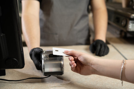 Contactless payment concept, woman customer holding credit card near nfc technology on counter, customer pays transaction on cashier rfid terminal in restaurant store, closeup viewの写真素材