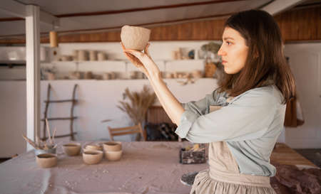 . woman artist sculpts from wet clay in studio. ceramist makes handicrafts from ceramics. female industriousness concept. copyspace.の写真素材
