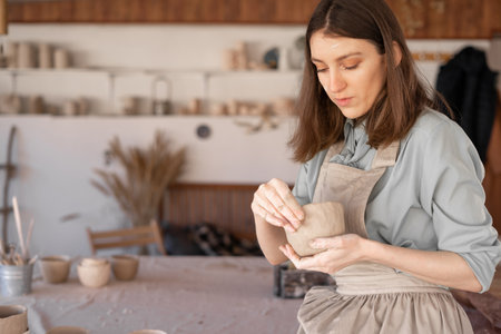 A young female master potter in the studio sculpts a clay pot. Banner. copyspace.の写真素材