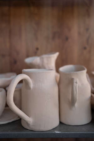 Ready-made ceramic dishes, handmade jugs on a shelf or shop window. Artistic concept, selective focus.の写真素材