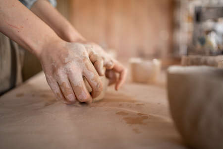 Small handmade pottery business the process of modeling and molding a clay jar in a studio or workshop. Close-up of the hand of a craftsman woman.の写真素材