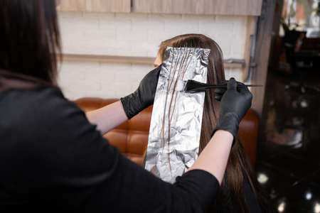 Closeup and cropped picture hairdresser holds the brush and dyes the hairの写真素材