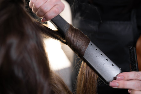 The hairdresser is working on a female hairstyle in the salon. close-up of the hands of the master...
