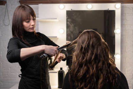 The hairdresser is working on a female hairstyle in the salon.の写真素材