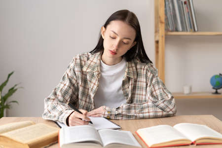 focused motivated girl college student studying with books, home education, doing homework, education conceptの写真素材